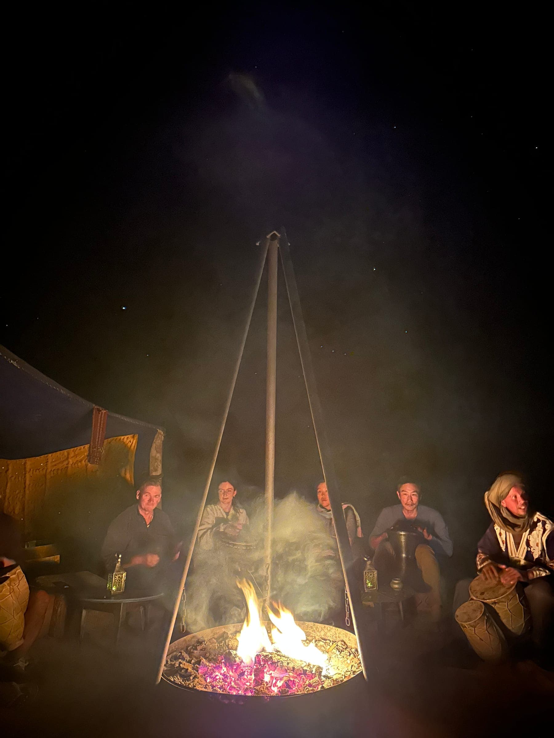 Travellers gathered around the campfire at our desert camp at night